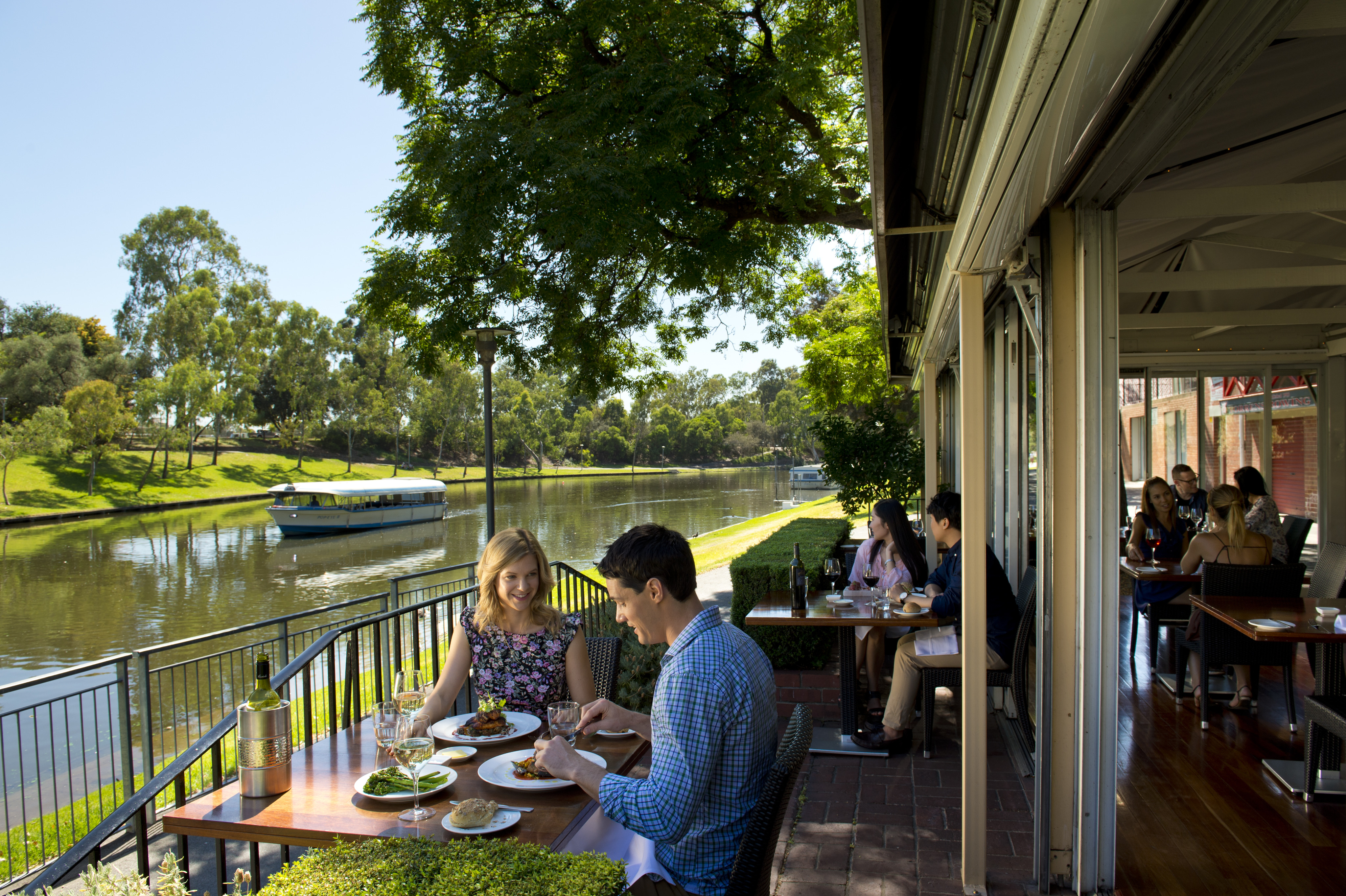 Jolleys Boathouse, people sit outside overlooking the River Torrens