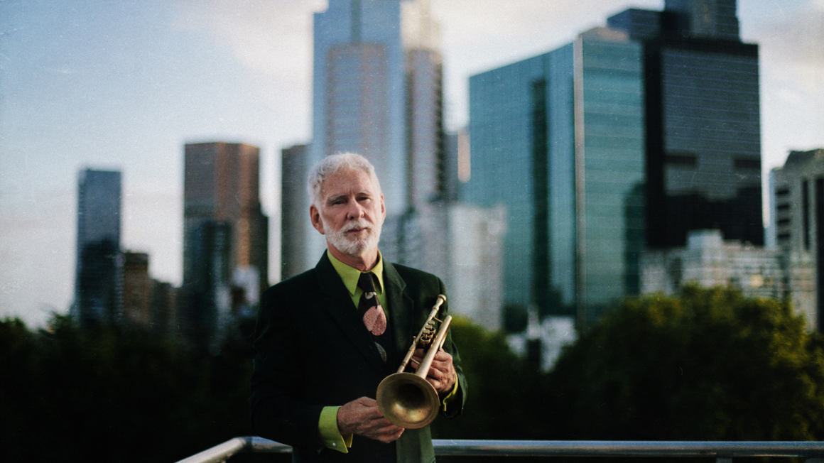 Vince Jones holding his trumpet against city backdrop