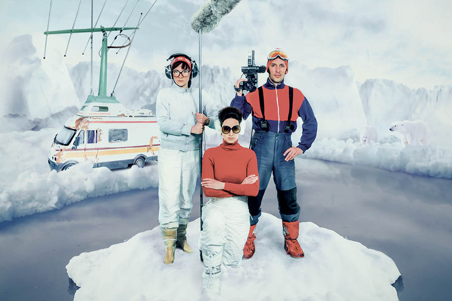 Three actors standing in the arctic with film gear