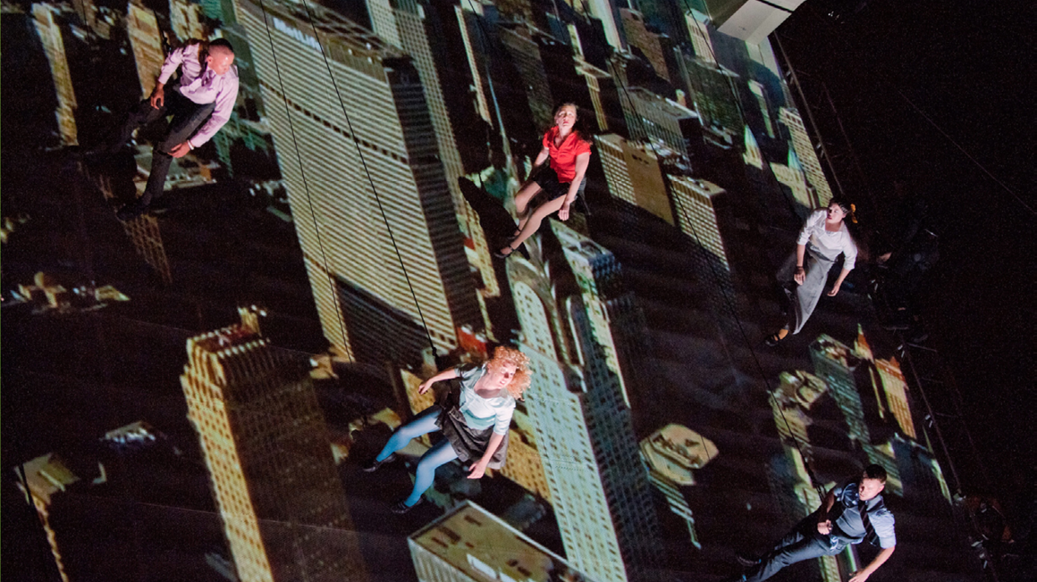 A group of people hanging from harness's from skyscraper reflections
