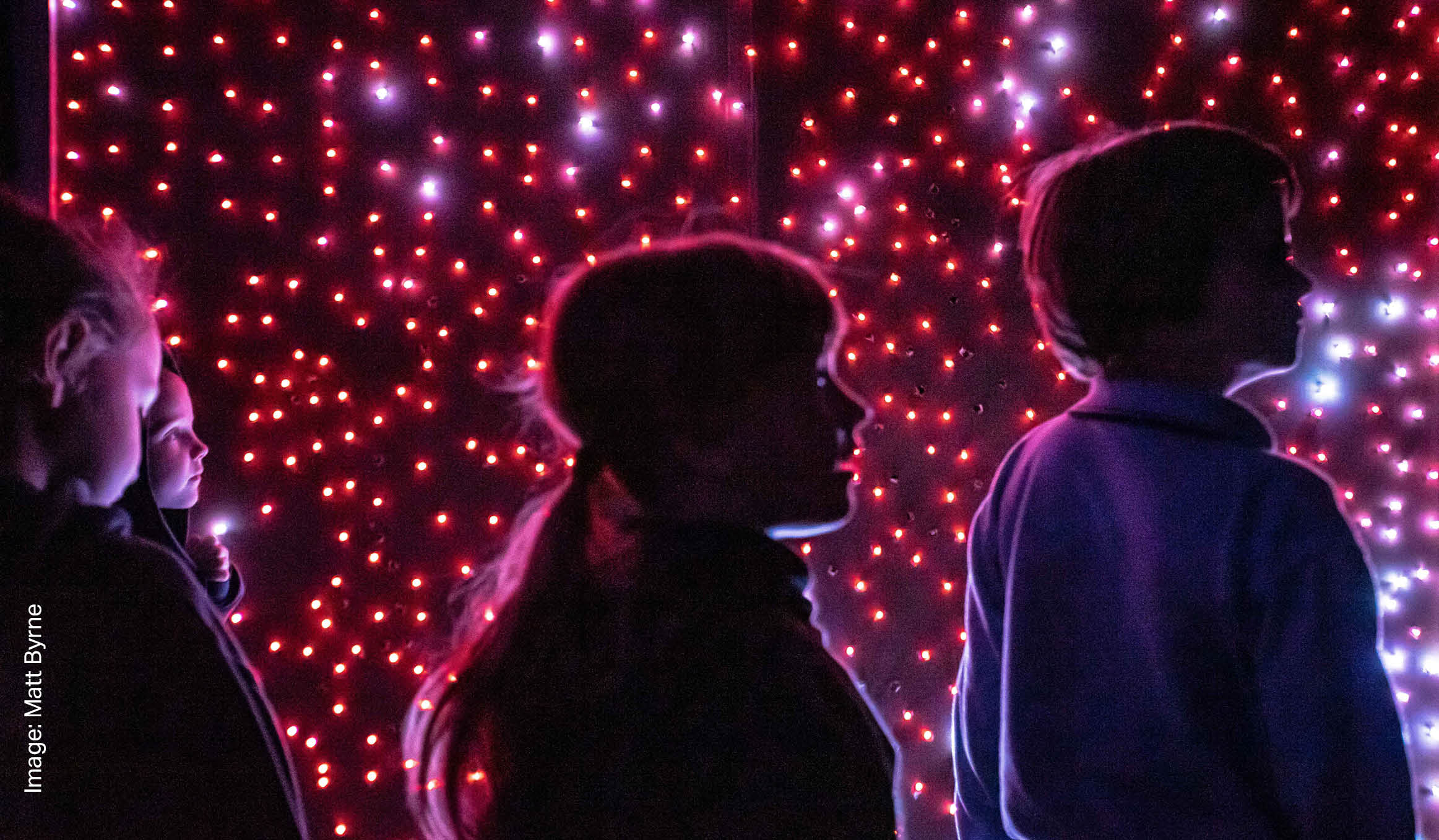 Silhouettes of children against pink speckled lights