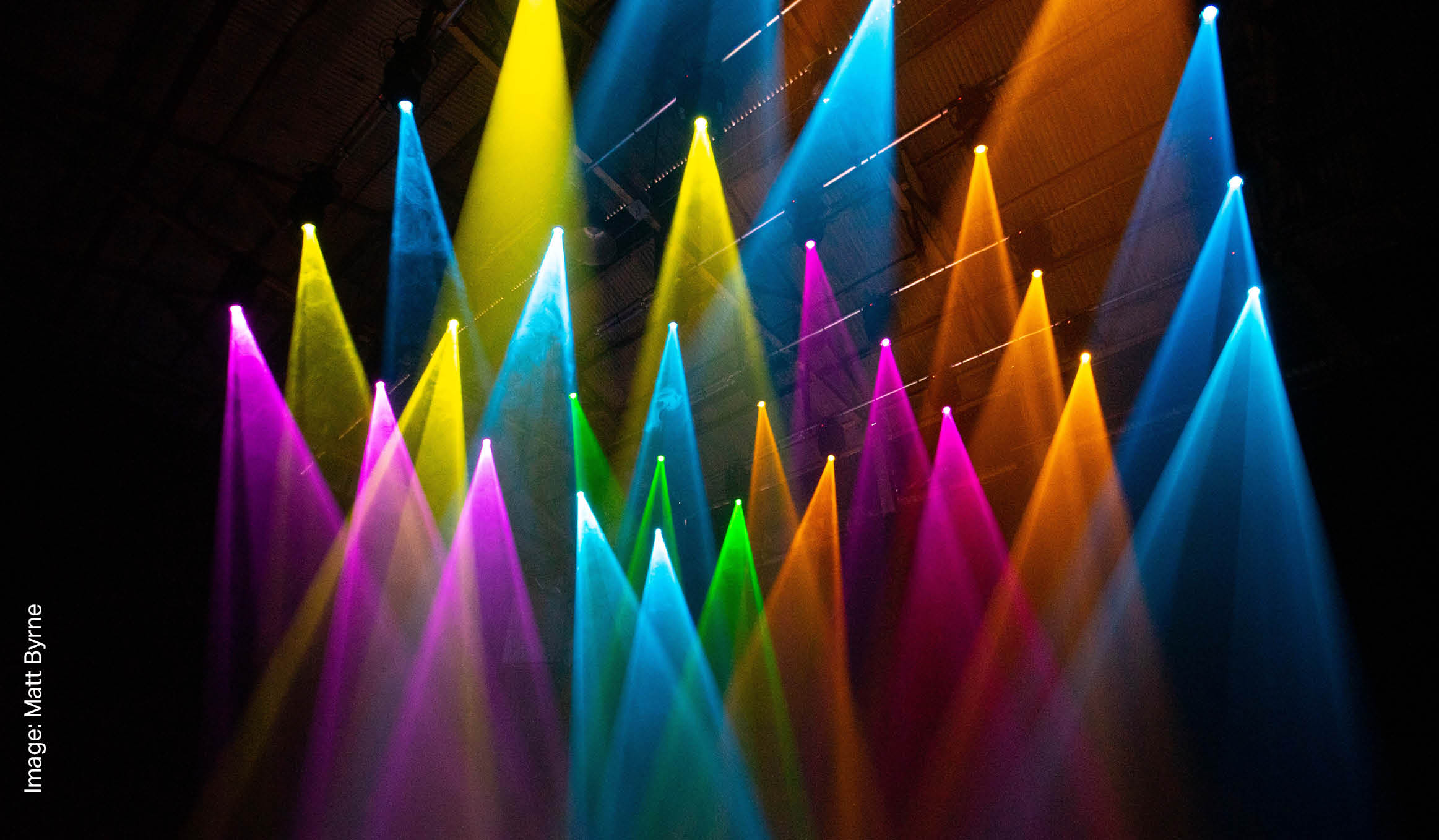 Rainbow lights coming from different angles against a black dark room